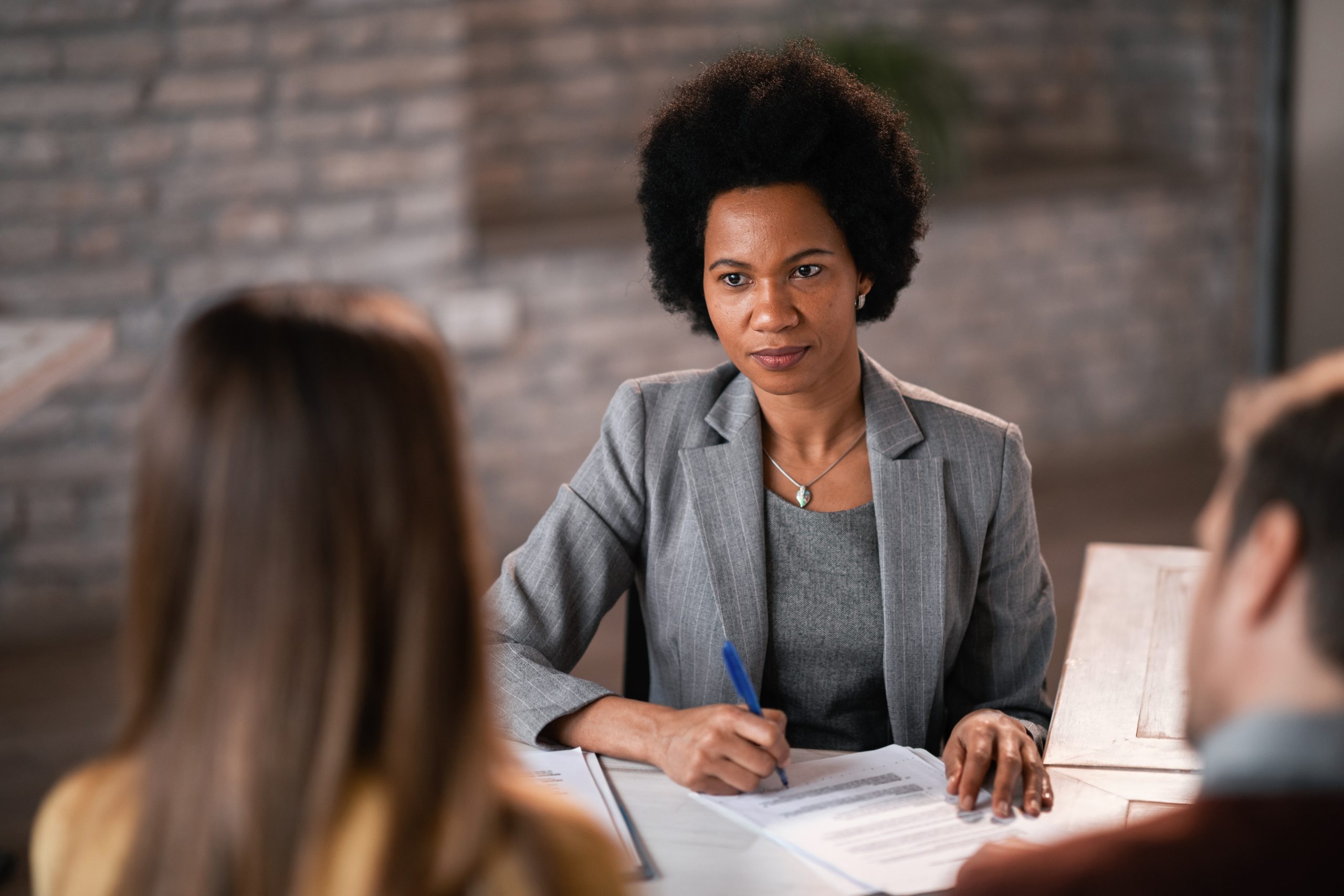 African American bank manager having an interview with her clients and filing paperwork during the meeting.